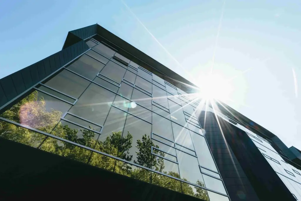 fenêtre de bâtiment baignée de lumière directe du soleil, créant un éblouissement intense à l'intérieur de la pièce. Sans film anti-reflet, la luminosité excessive rend difficile la visibilité à travers la vitre et crée une atmosphère éblouissante et inconfortable. L'absence de protection contre les reflets solaires peut entraîner des niveaux élevés d'éblouissement et une augmentation de la chaleur à l'intérieur.
