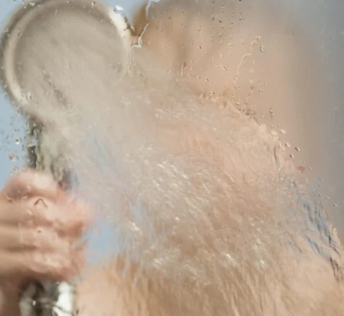 Enfant dans la douche arrosant une paroi vitrée embuée