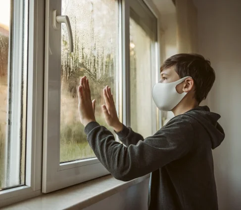 side-view-little-boy-with-face-mask-looking-through-window