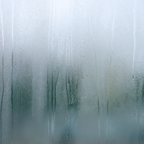 Fenêtre recouverte de buée sans film anti-buée, illustrant la différence de protection contre la condensation et l'humidité.